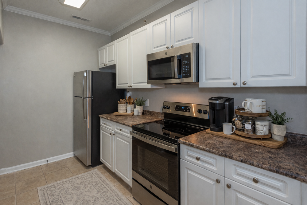 Modern kitchen with white cabinets, stainless steel appliances, and brown countertops.