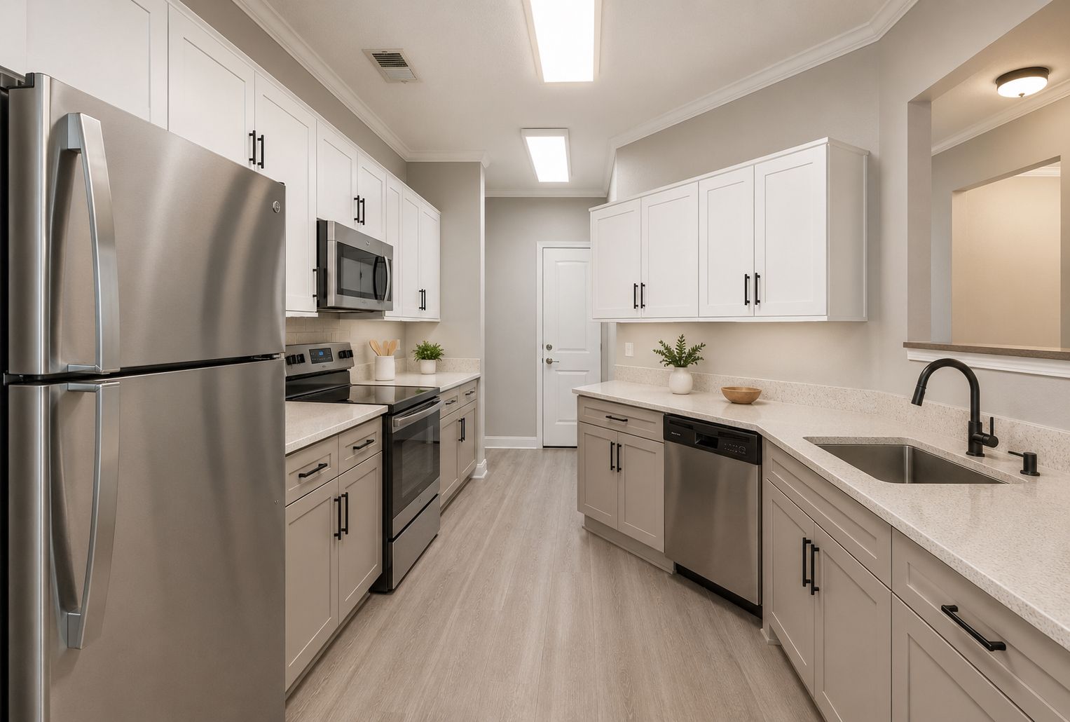 Modern kitchen with white cabinets, stainless steel appliances, and light wood flooring.