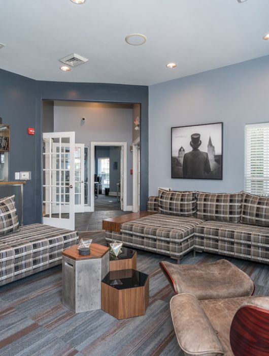 Modern living room with plaid sofas, lounge chair, wooden shelves, and large windows letting in natural light.